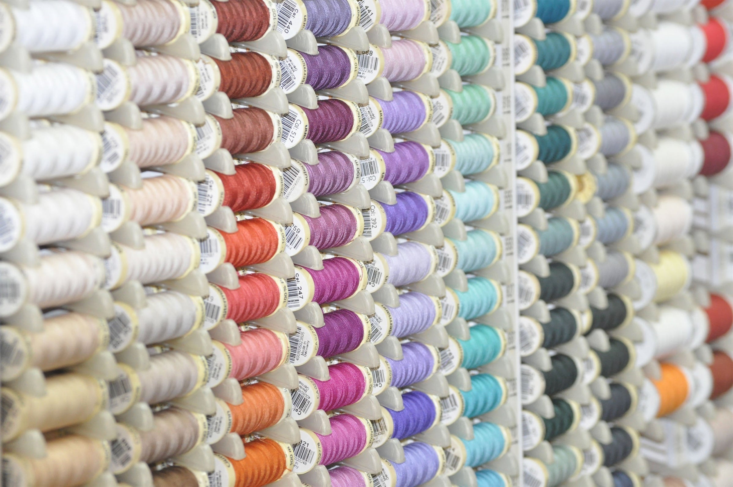 Gutermann 100m thread spools on a stand, offering premium sewing thread for various sewing projects - available at Fabric Collection Brisbane.