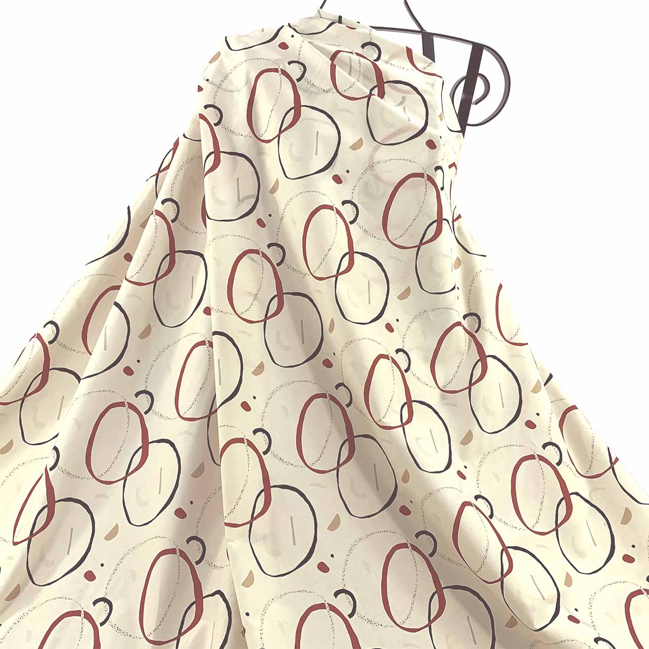 Linen print with circular pattern in navy, cayenne colours draped against a white background - Fabric Collection