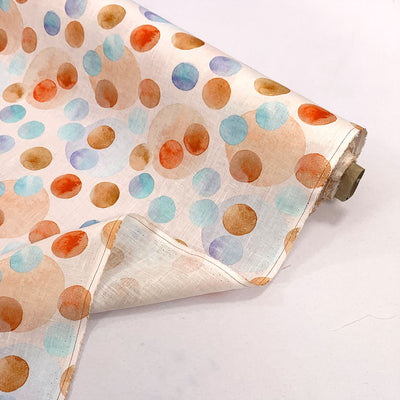 Roll of fabric with colorful polka dot pattern on a white background